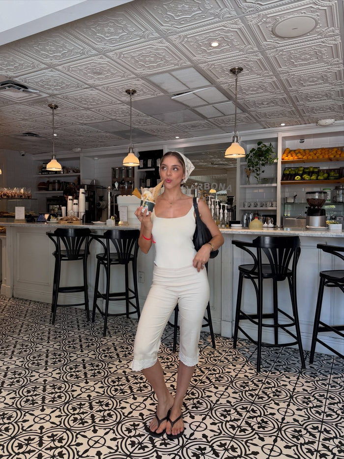 Clienta con blusa ivory y capri arena en un café de Nueva York