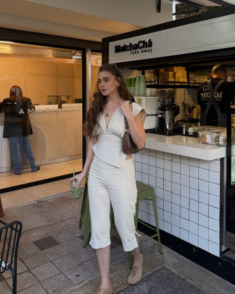 Clienta con blusa ivory y capri arena en un café de matcha