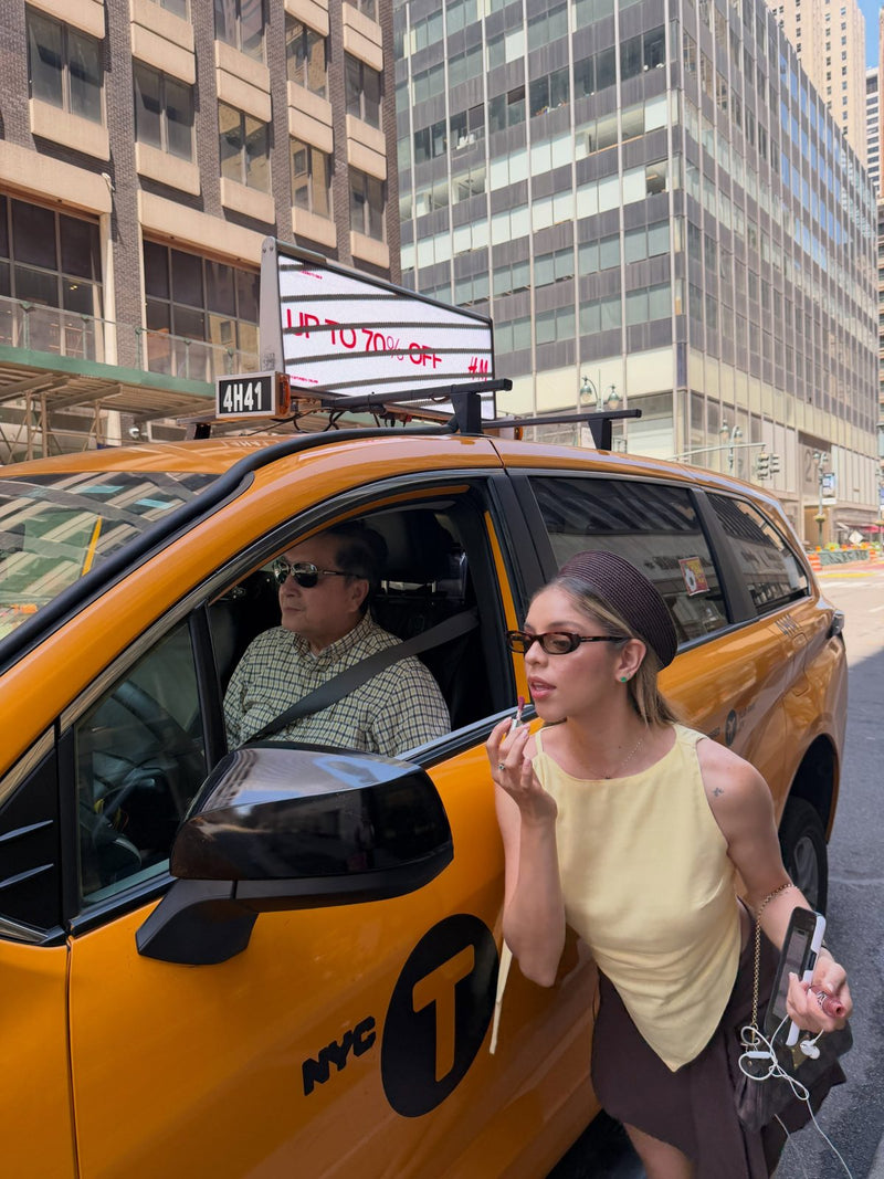 Blusa amarilla y falda café/amarillo frente a un taxi de Nueva York